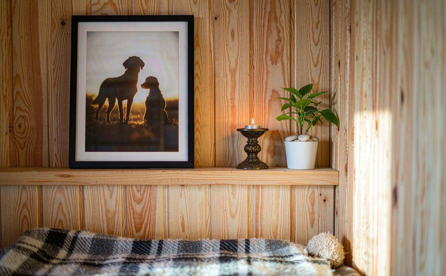 A cozy home memory corner with pet portraits, candles, and keepsakes arranged on a wooden shelf